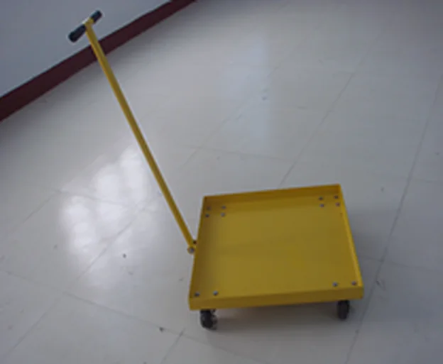 Yellow drum dolly platform with long pull handle on the workshop floor
