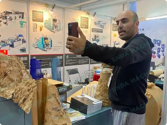 Man taking a selfie at an industrial trade show booth with product display boards in the background