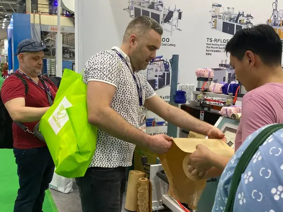Men at a trade show booth inspecting a sheet of abrasive material