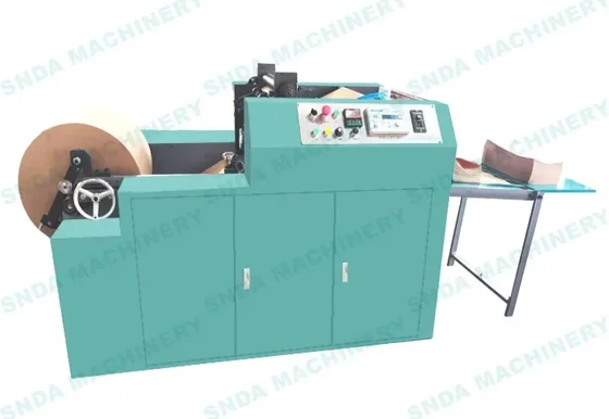 Teal industrial bag making machine with control panel, material roll, and output table on white background