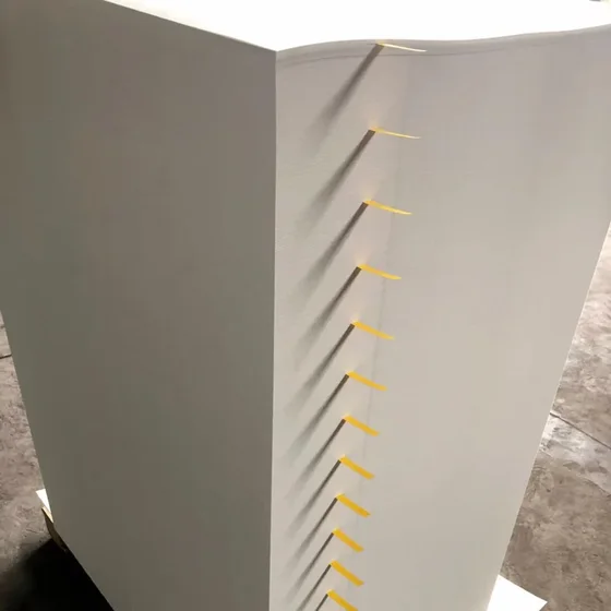 Large stack of white sheets with yellow separator tabs on a wooden pallet on a concrete floor