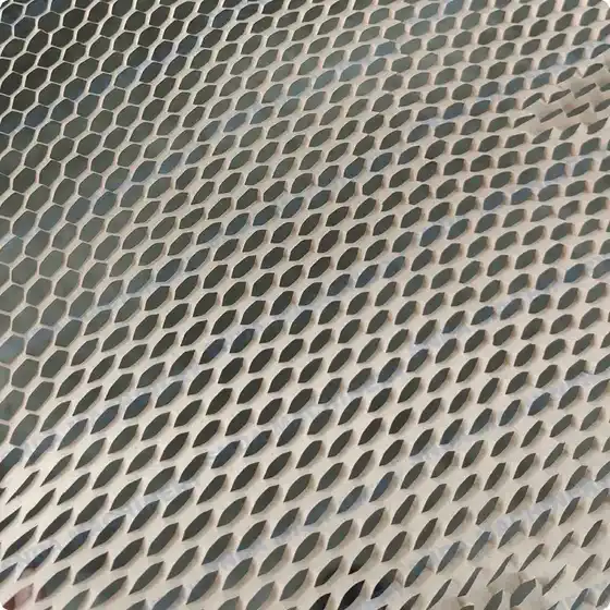Close-up of white expanded mesh sheet with elongated hexagonal openings over a dark background