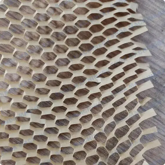 Close-up of white honeycomb paper wrap with hexagonal cells laid over a wood-grain surface, edges slightly torn