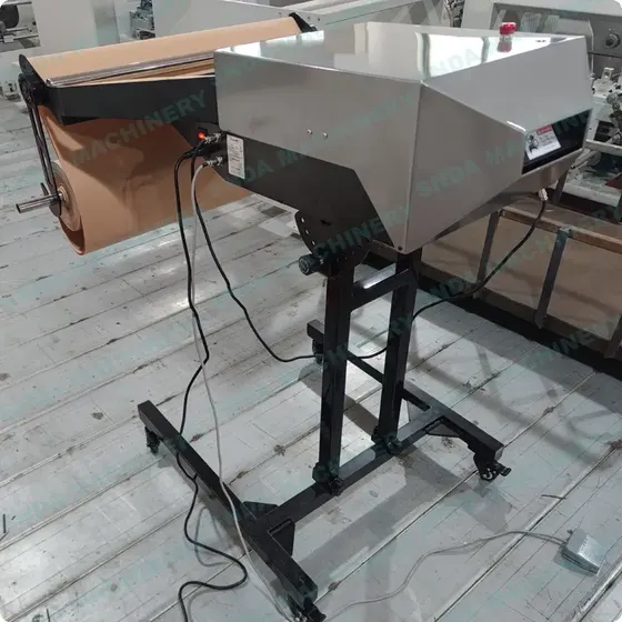Industrial machine with a cardboard roll and a stainless steel housing mounted on a black stand