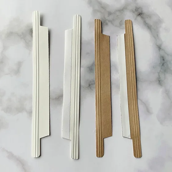 Two white and two kraft brown flat cardboard strips with lengthwise ridges, arranged vertically on a marble surface