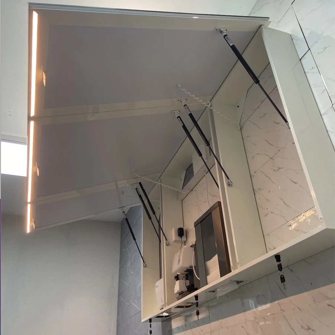 Integrated touch free soap dispenser inside a public washroom mirror cabinet