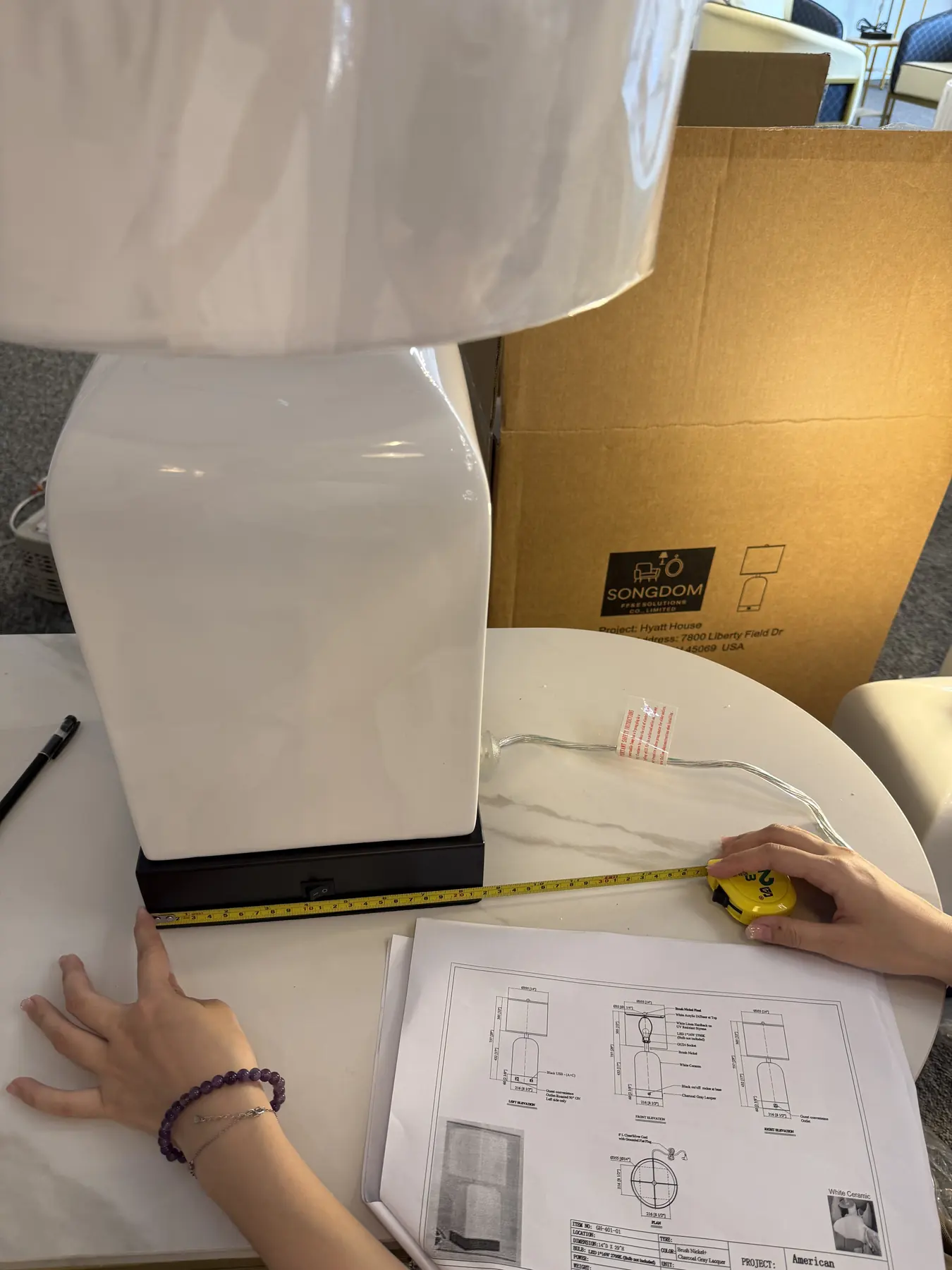 Songdom engineer checking a hotel table lamp against the technical drawing during QA inspection