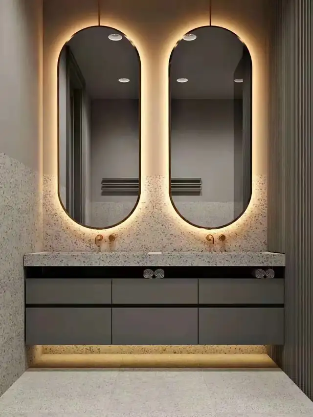 Vanity cabinet with lighted mirrors above a stone countertop