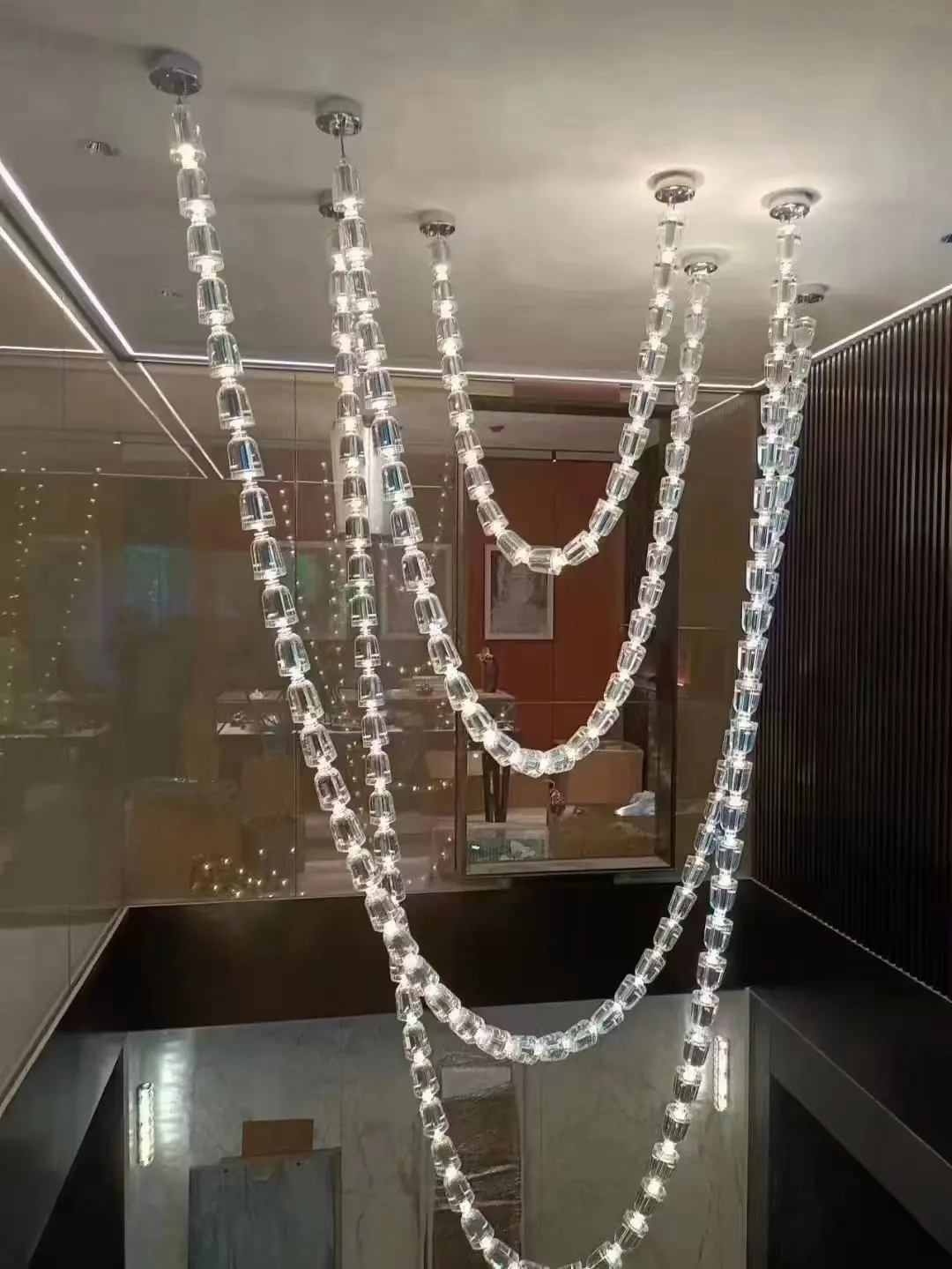 Long crystal strand chandelier in a double height space