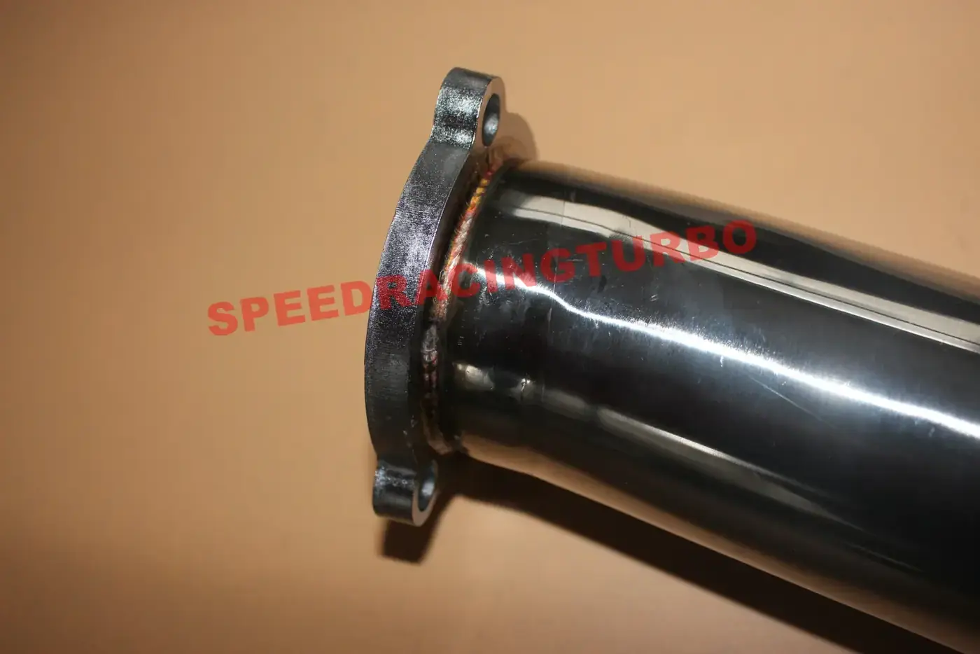Close up of a polished stainless turbo downpipe with a bolted flange joint
