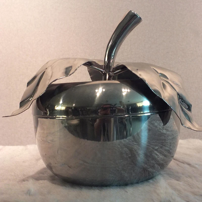 Mirror polished stainless steel apple ornament on a modern office desk