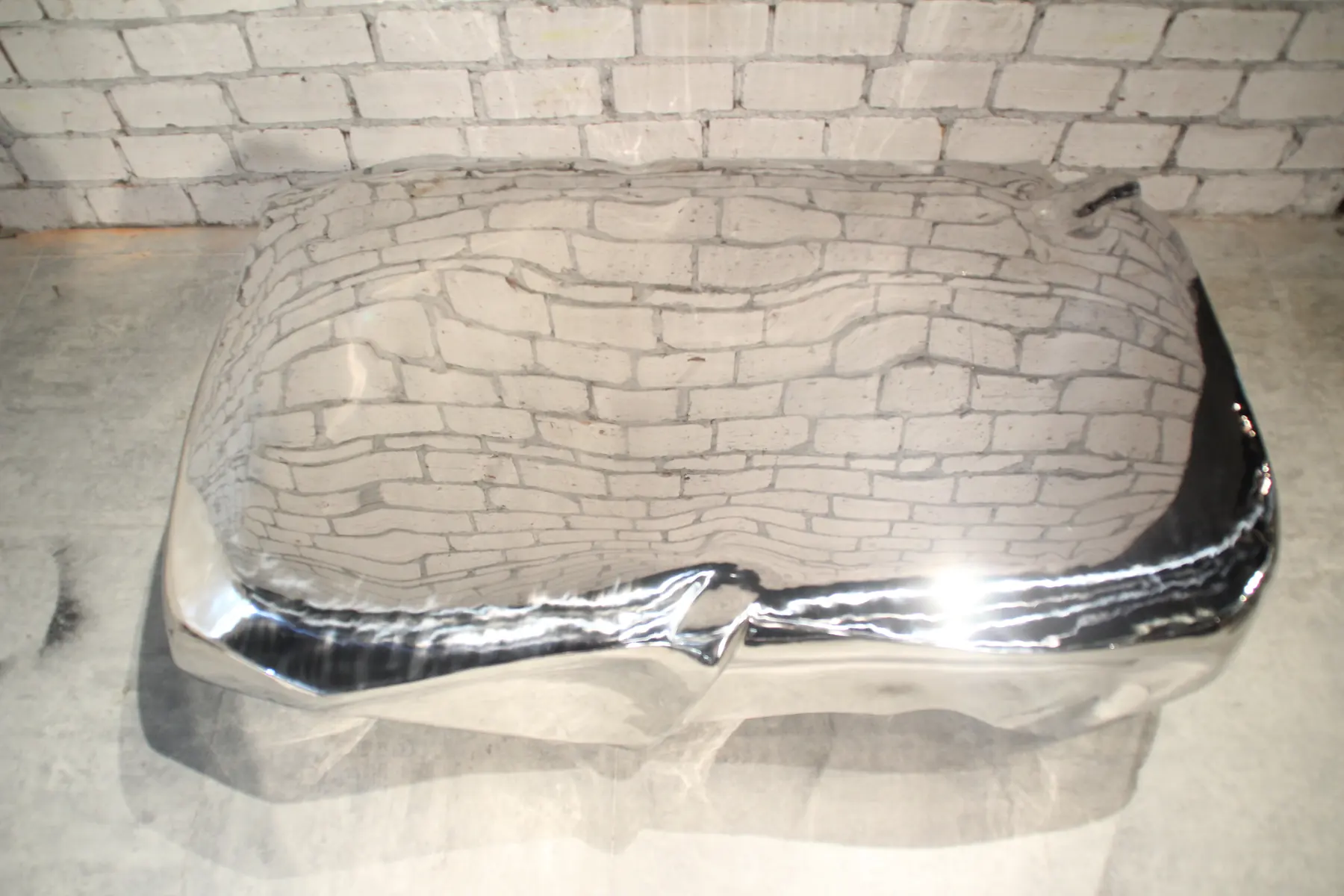Sculptural stainless steel coffee table with mirror polish in a modern living room