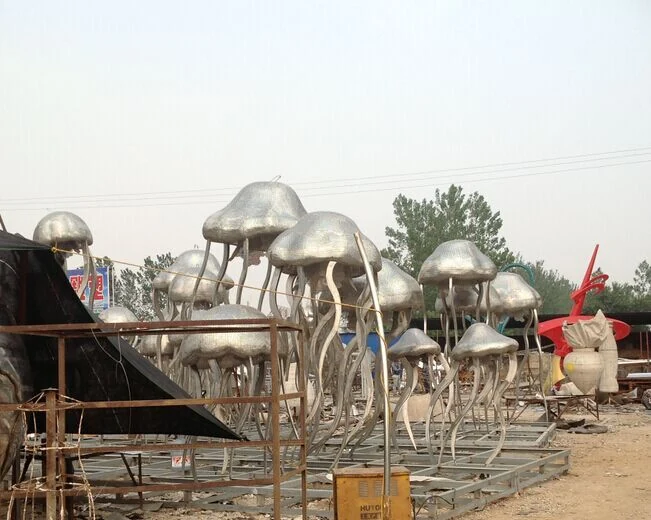 Group of mirror polished stainless steel jellyfish sculptures arranged in a swarm on a park plaza