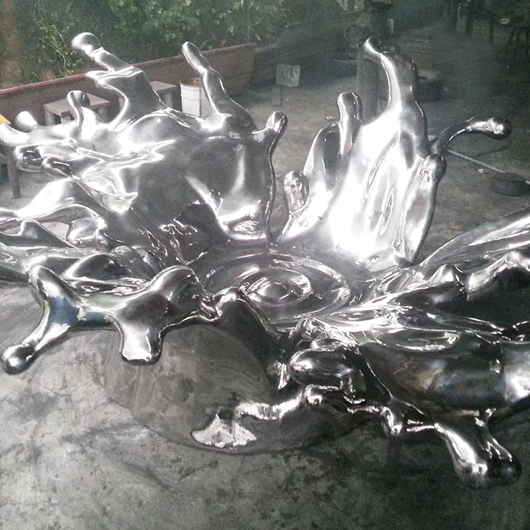 Stainless steel water splashing sculpture with water flowing from a curved metal form