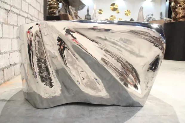 Side view of a sculptural coffee table showing its hand forged form and smooth surface