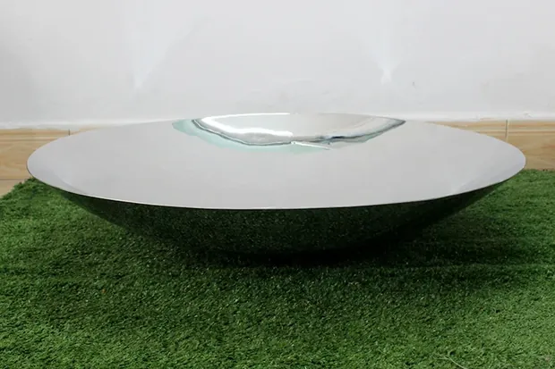 Wall-mounted concave mirror sculpture with a reflective surface in a hotel lobby