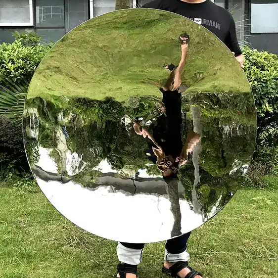 Close-up of a mirror-polished stainless steel hemisphere showing reflection of sky and architecture