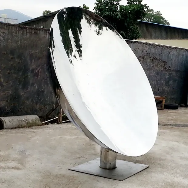 Reflective concave stainless steel sculpture capturing sky and trees in a garden