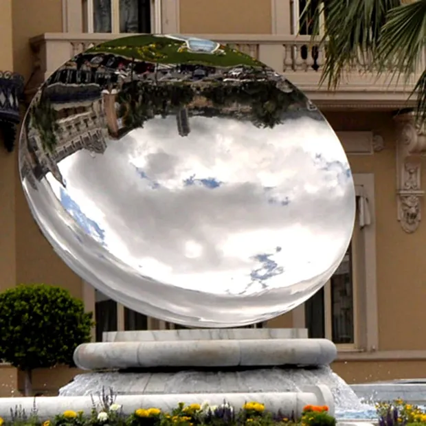 Concave mirror sculpture with mirror polish installed in a garden setting