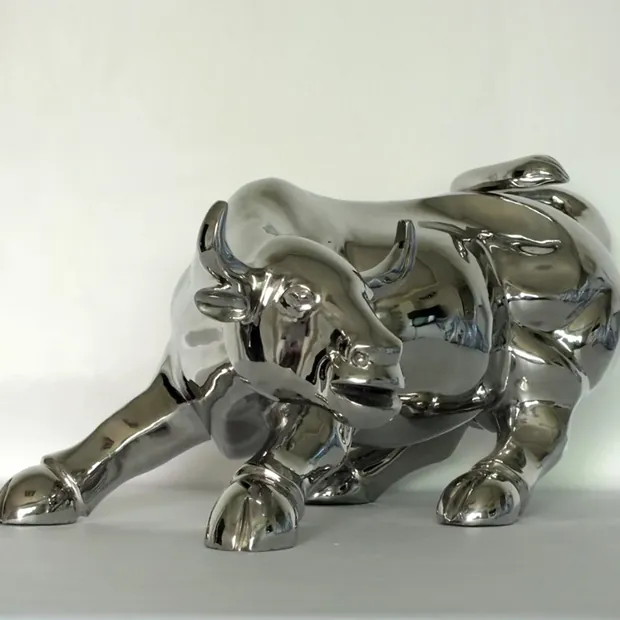 Mirror polished stainless steel cow sculpture standing in a public plaza