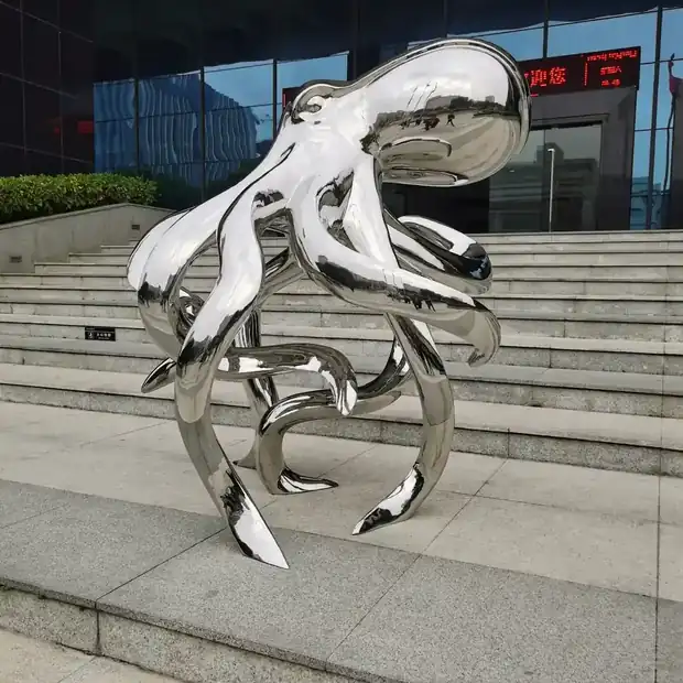 Large stainless steel octopus sculpture in a public plaza with tentacles extending outward