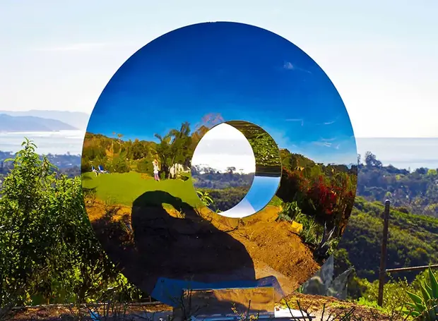 Close-up of the polished surface of a stainless steel outdoor sculpture showing reflections
