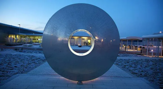 Sculpture installed at a plaza entrance with people walking nearby
