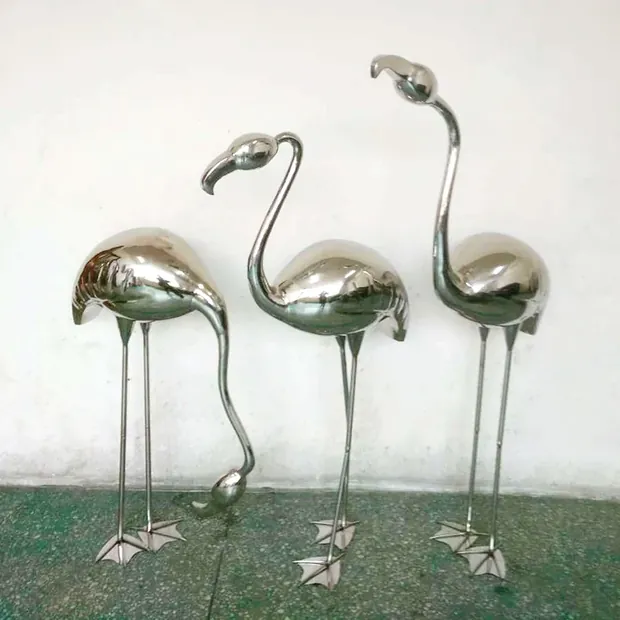Hand forged stainless steel flamingo sculpture standing on a park plaza