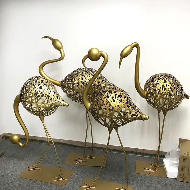 Large stainless steel flamingo sculpture in mirror polish reflecting the sky and trees