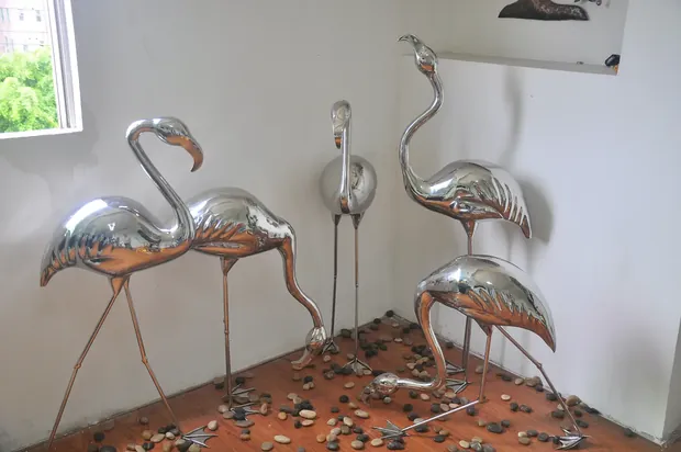 Flamingo sculpture placed in a shallow water feature with reflective surface