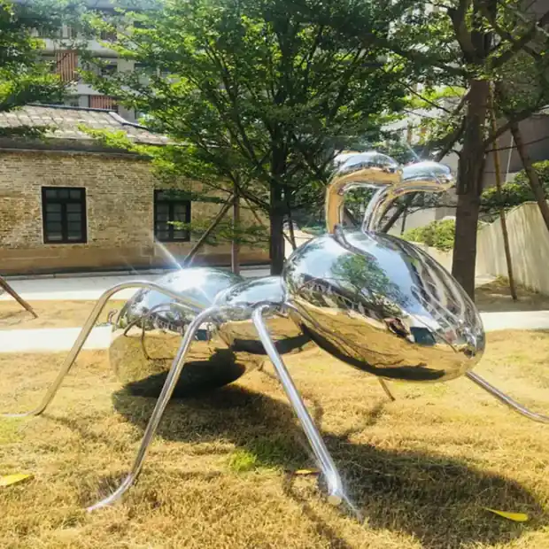 Large ant sculpture installed at a hotel entrance with people walking nearby