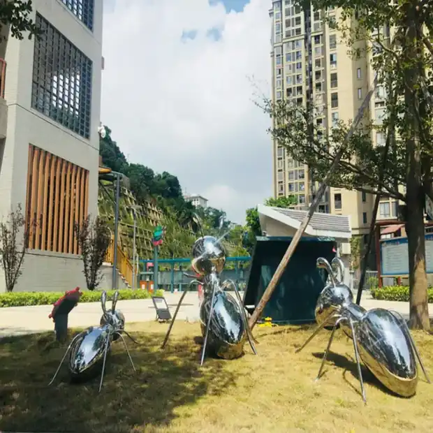 Close-up of mirror polished stainless steel ant sculpture reflecting the sky