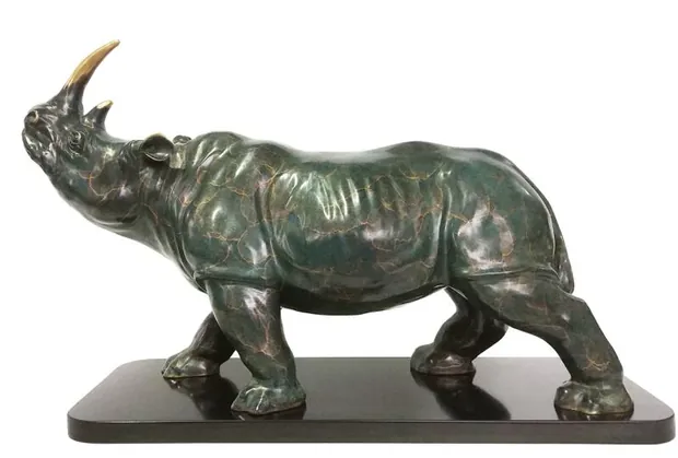Brass rhinoceros sculpture standing on a plinth in a modern interior space