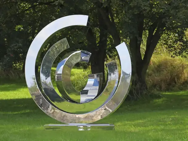 Large stainless steel ribbon sculpture in a hotel lobby, reflecting light and architecture