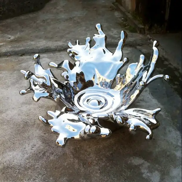 Close-up of mirror polished stainless steel sculpture showing water droplets in motion