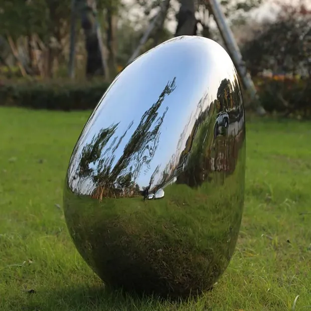 Stainless steel pebble sculpture reflecting surrounding planting