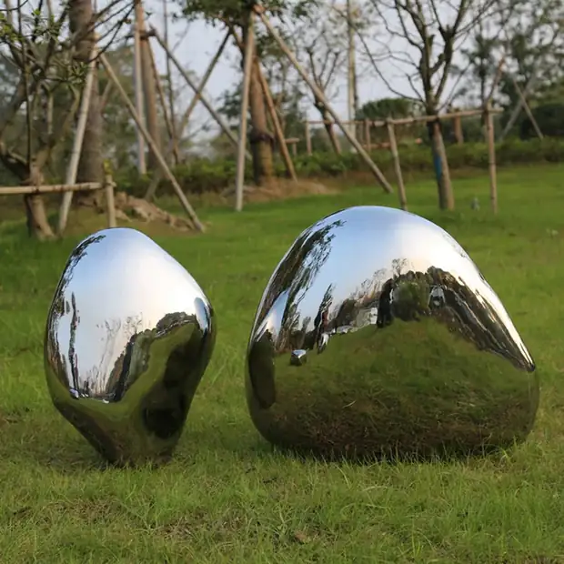 Group of forged stainless steel pebbles beside a shallow water feature