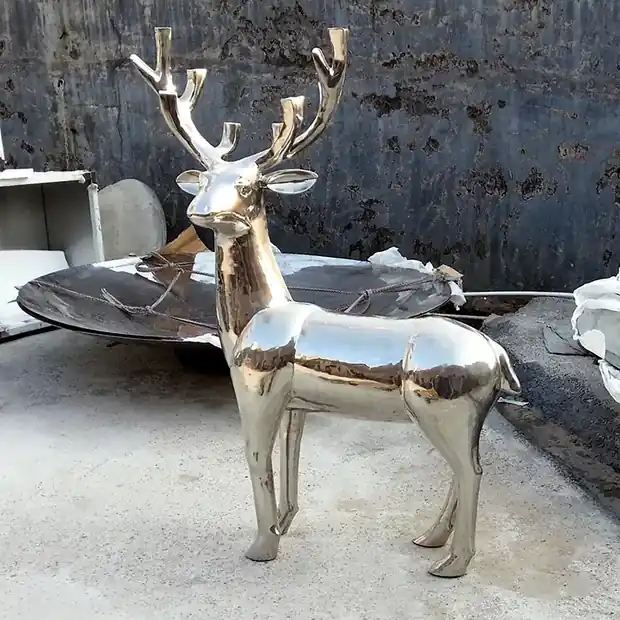 Sika deer sculpture installed at a building entrance with reflective surface catching light