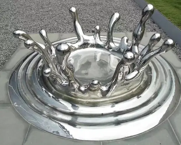 Water drop and flower sculpture reflecting light in a public plaza