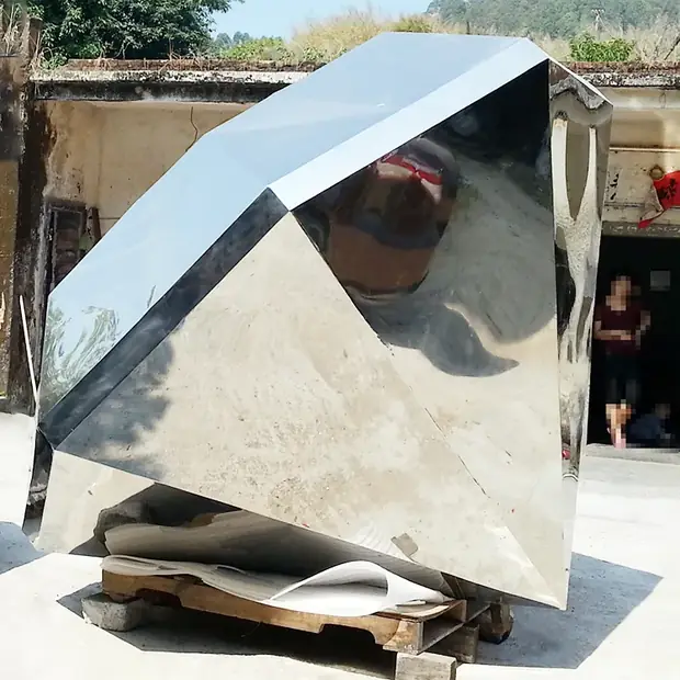 Super Diamond sculpture reflecting sky and surrounding architecture