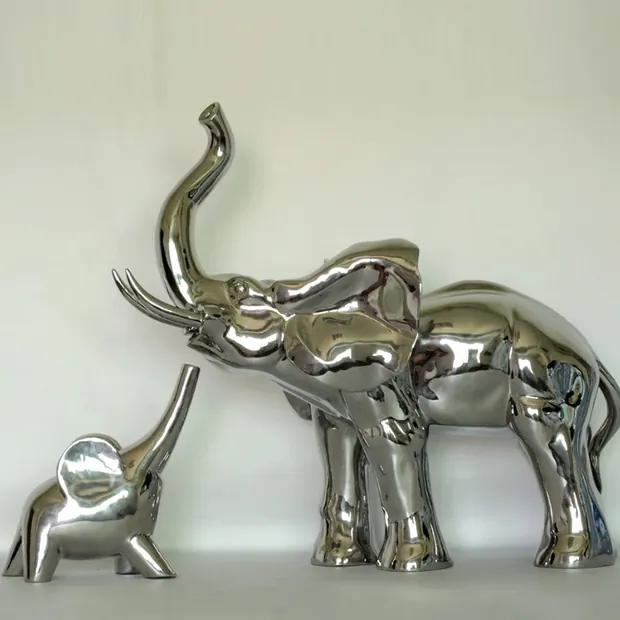 Lifelike stainless steel elephant sculpture with mirror finish in a garden setting