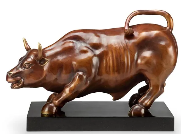 Cast copper Wall Street Bull sculpture on a wooden desk with a polished finish