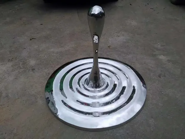 Mirror polished water pattern sculpture reflecting light in an interior space