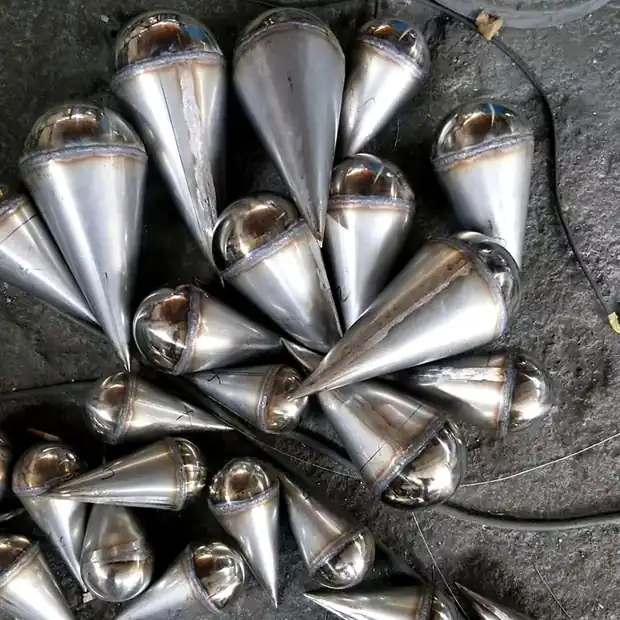 Group of mirror polished water drop sculptures on a plaza floor