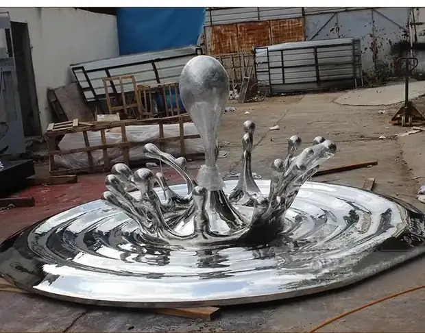 Close-up of a mirror polished stainless steel water droplet sculpture reflecting light
