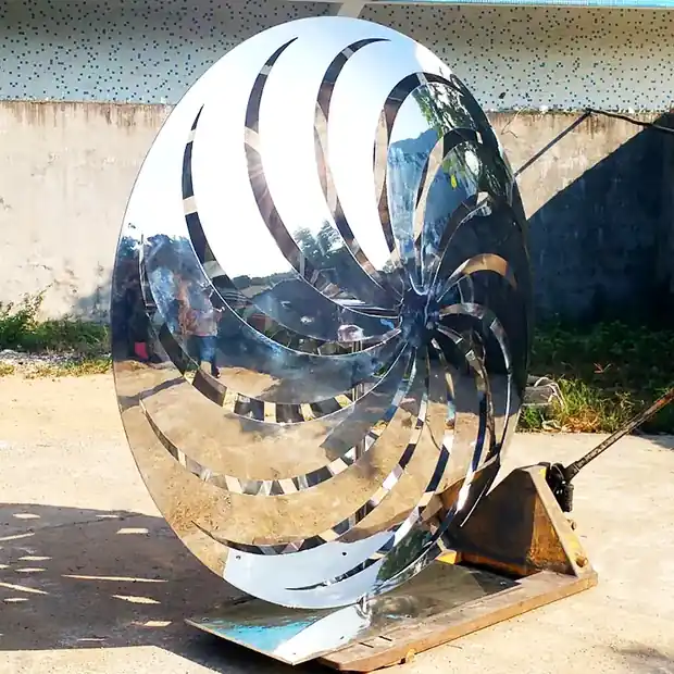 Windmill butterfly sculpture with rotating stainless steel wings in a park setting