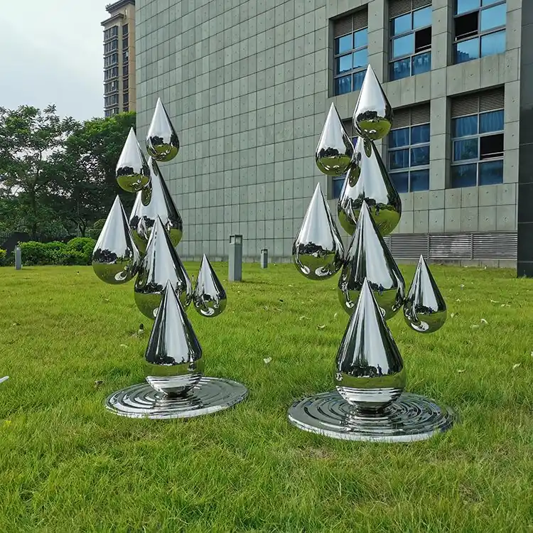 Cluster of abstract stainless steel water droplet sculptures on a plaza floor