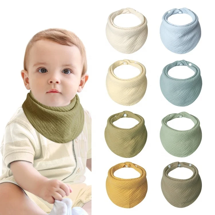 Multiple bandana bibs laid out in neutral colour, folded and stacked
