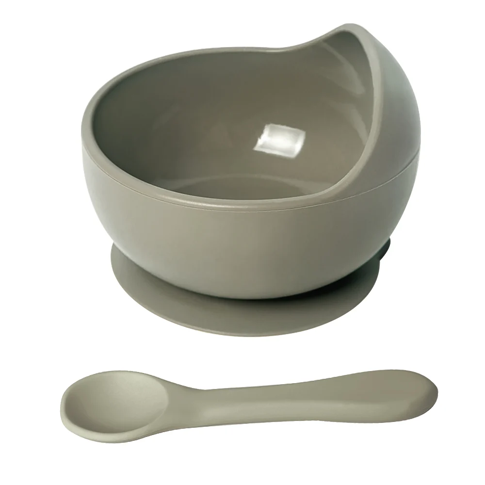 Grey suction silicone bowl with spoon placed on a flat surface