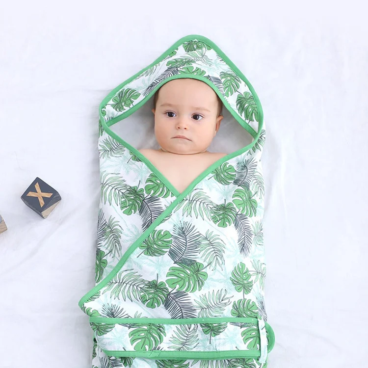 Pink cotton swaddle blanket wrapped around a baby model, showing adjustable fit